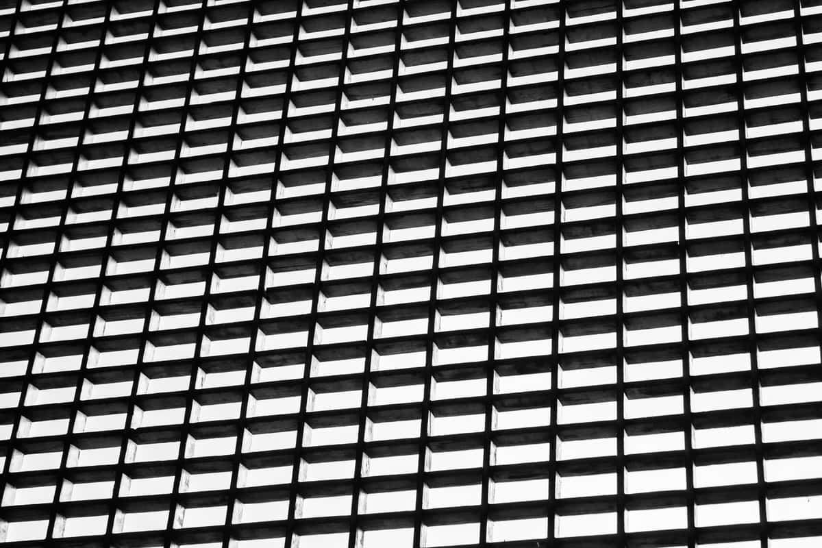 A repeating grid of identical building modules seen head-on in black and white